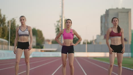 A-group-of-women-at-the-track-and-field-competition-warm-up-and-prepare-for-the-race.-Concentrating-on-the-start-line-at-the-stadium